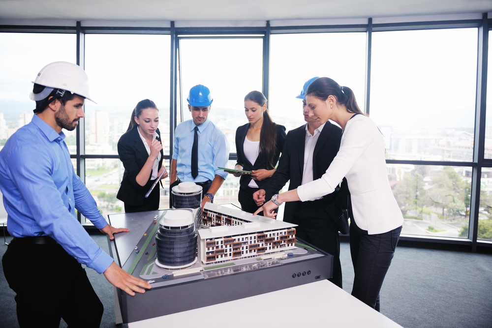 business people group on meeting and presentation in bright modern office with construction engineer architect and worker looking building model and blueprint planbleprint plans